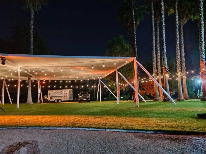 Toldo de Carpas HyH con iluminación nocturna en un jardín